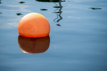 Orange buoy reflection on a calm day.