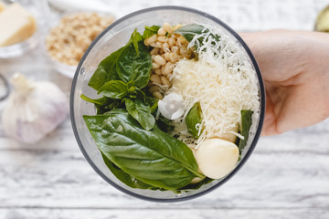 The process of making pesto sauce in a blender from cheese, pine nuts, olive oil, basil, garlic on...