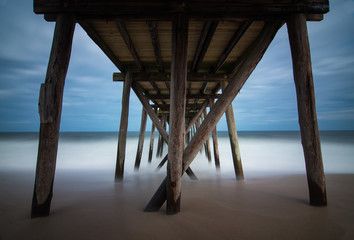 Under old wooden fishing pier with calm ocean