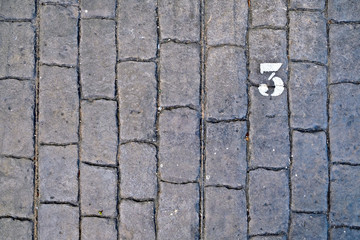 3, number three, white stencil number on cobblestone surface.