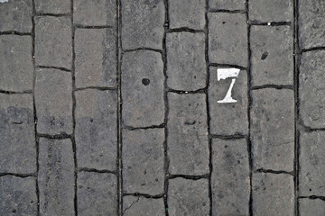 7, number seven, white stencil number on cobblestone surface.
