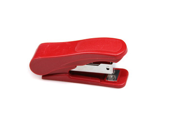 A close up image of a small red stapler isolated on a clean, white background