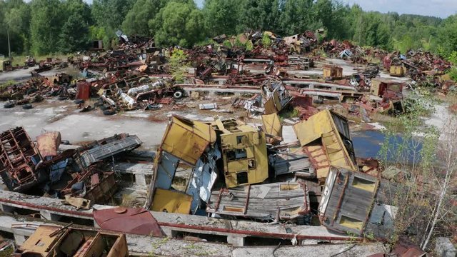 Aerial view of old rusty garbage, car debris, wheels and other radioactive metal abandoned in exclusion zone. Drone shot of wrecked iron change houses used during liquidation of Chernobyl accident