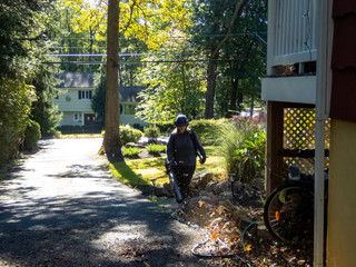 woman cleaning fallen leaves with leaves blower in the garden in the fall