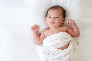 Selective focus medium shot of 0-1 months beautiful relax asian newborn baby girl infant lying down on the soft white blanket baby sleeper. Mother and young baby health care concept.