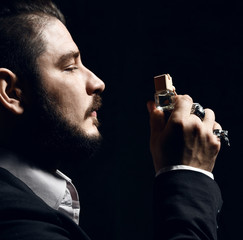 Brutal man with beard and modern hairstyle smell auto perfume wear business classic suit