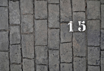 15, number fifteen, white stencil number on cobblestone surface.