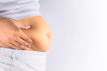 Fat woman is catching her belly area that has excess fat.