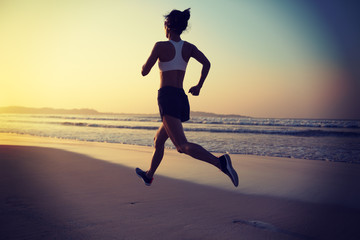 Fototapeta na wymiar Woman running on sunrise beach