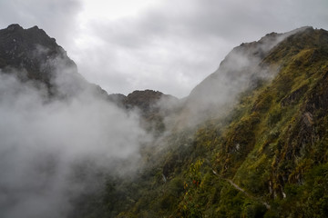 Low hanging clouds around the green mountains that stretch through the Inca trail towards Machu Picchu