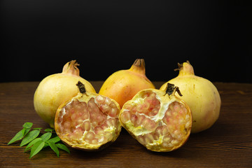 Yellow pomegranate fruit on old wooden table with the dark background.