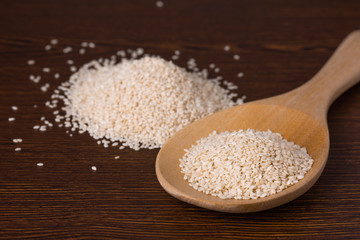 Raw cereal, white sesame seeds on wooden spoon natural healthy food concept