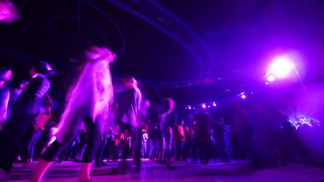 Time-lapse fast motion of disco party all night long with silhouettes of people dancing on the dancefloor with purple disco lights glowing