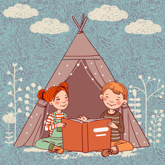 Cute boy and girl in a tepee tent reading book
