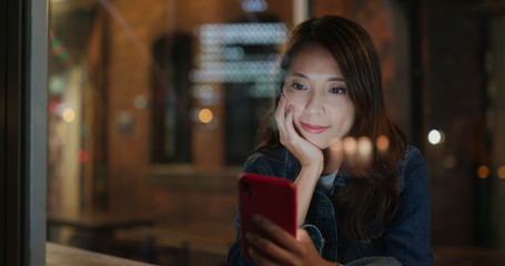 Woman use of mobile phone in coffee shop inside coffee shop, window glass reflection