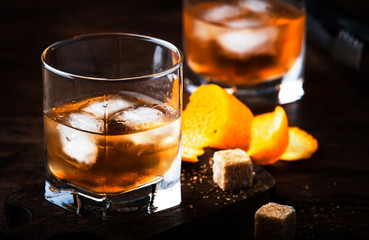 Old Fashioned - classic alcoholic cocktail with bourbon whiskey, bitter, cane sugar and ice in retro glasses on vintage bar counter, place for text