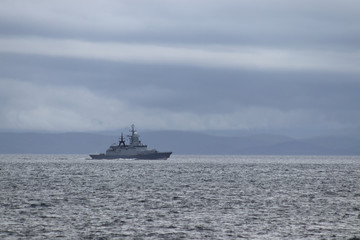 Warship moving on the horizon under the cloudy sky.