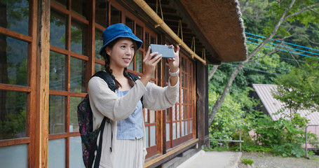 Woman visit Japanese old village house and use of mobile phone to take photo