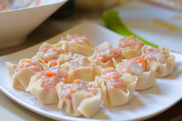 Close up raw Traditional chinese food dumpling called Shumai in Thailand called kanom jeep in white plate . Cooking by steam in bamboo basket.