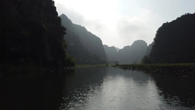 Quiet and magic moment on a rowing boat in the river between limestones mountains of Tam Coc, wonderful and famous UNESCO world heritage site in Vietnam