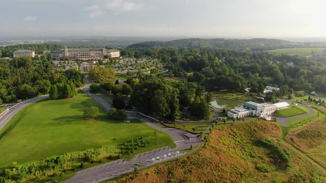 Descending aerial trucking shot of manicured gardens and beautiful scenery on a hillside during magic hour