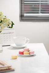 Office table desk. Feminine desk workspace frame with calendar, diary, hortensia bouquet, macaron and coffee on white background. ideas, notes or plan writing concept