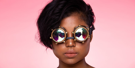 Tanned Skin Teenager Fashion Model looks at camera for shooting new collection Sunglasses.  Beautiful Asian Woman trend make up wear Kaleidoscope Glasses with colorful, studio lighting pink background