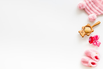 Booties and hat for newborn girl with rattle and dummy on white background top view mock up