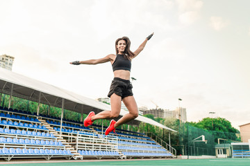 Fototapeta na wymiar beautiful fit sporty woman jumping on the stadium high in the air