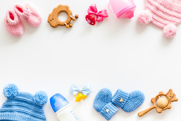 Blue and pink knitted footwear, hat, dummy, rattle and bottle frame for baby on white background...