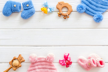 Blue and pink knitted set for kids, rattle, dummy on white wooden background top view space for text