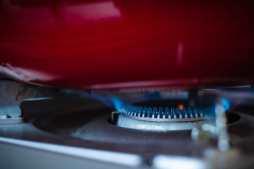 Close up gas stove with blue flames of burning gas with red pan, cooking food concept.