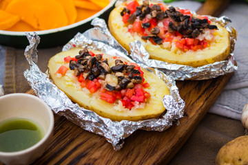 Baked stuffed potatoes with vegetables in foil. Homemade vegan food. 