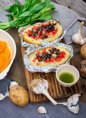 Baked stuffed potatoes with vegetables in foil. Homemade vegan food. 