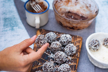 Woman hands holds coconut sweet balls. Energy protein dessert with dates, cocoa, peanut butter.