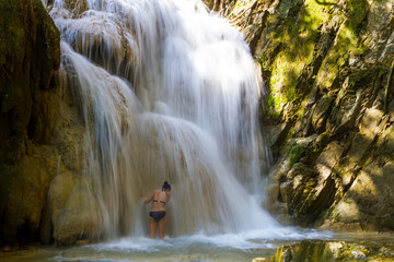 Woman with bikini black play water at Erawan Waterfall