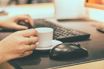 Woman hand holdding coffee cup with working table