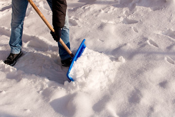 A teenager shoveling snow in his yard. The concept of a snowy winter.