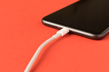 Smartphone on charge . On red background. Close up.