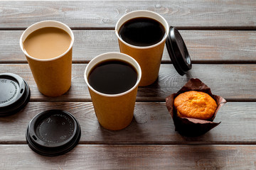 Coffee to take away, muffin on wooden background. Translation of the Russian text on the lid is Caution: contents hot.