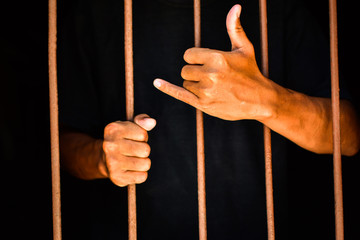 hand man lift up and hold steel in jail on black background.concept for prisoner,happy,detain,funny