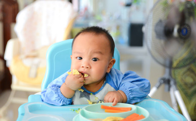 Asian baby boy 6 months old eating with Baby Led Weaning (BLW) method, Self-Feeding