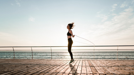 fit teenage girl with jump rope on a beach exercising and working out