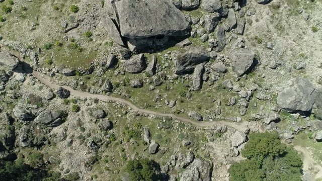 Aerial bird view shot of hiking path throug a lotof big and small rocks to gala gorropu on sardinia italy - by drone helicopter