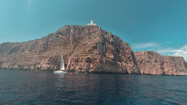 A Big Cliff From The Sea With A Lighthouse And A boat