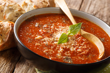 Homemade tomato puree basil soup with parmesan cheese close-up in a bowl with bread. horizontal