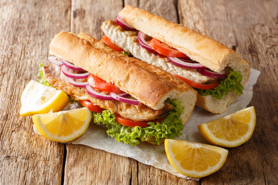 Turkish food sandwich balik Ekmek with grilled mackerel, tomatoes, onions and lettuce served with lemon closeup. horizontal