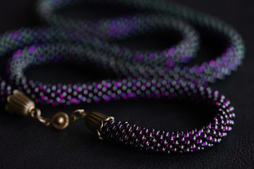 Close-up of a long violet bead necklace on a dark background