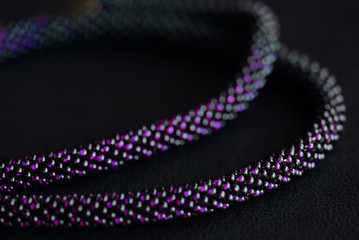 Fototapeta premium Close-up of a long violet bead necklace on a dark background