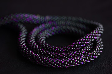 Close-up of a long violet bead necklace on a dark background